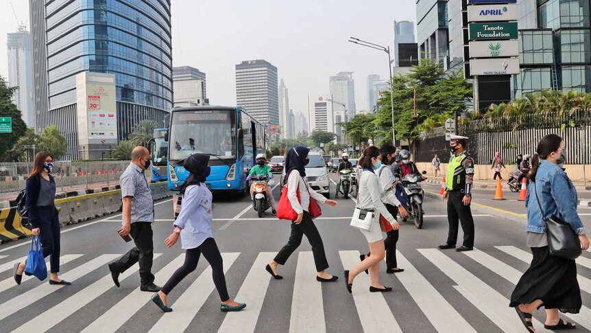 People cross a main road in Jakarta.