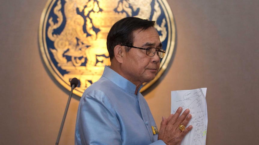 Thailand Prime Minister Prayuth Chan-ocha wears a blue shirt and walks to the right as he leaves a press conference