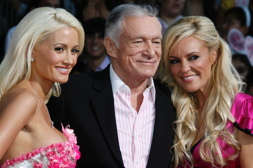 Playboy founder Hugh Hefner smiles with two Playboy Bunnies - Holly Madison and Bridget Marquardt - on his arms.