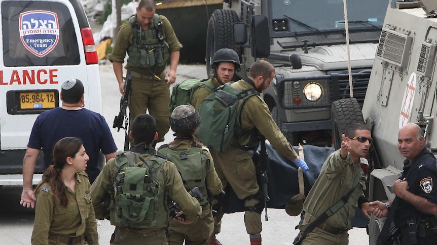 Israeli soldiers remove the body of a Palestinian assailant allegedly shot in head by an Israeli soldier