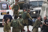 Israeli soldiers remove the body of a Palestinian assailant allegedly shot in head by an Israeli soldier