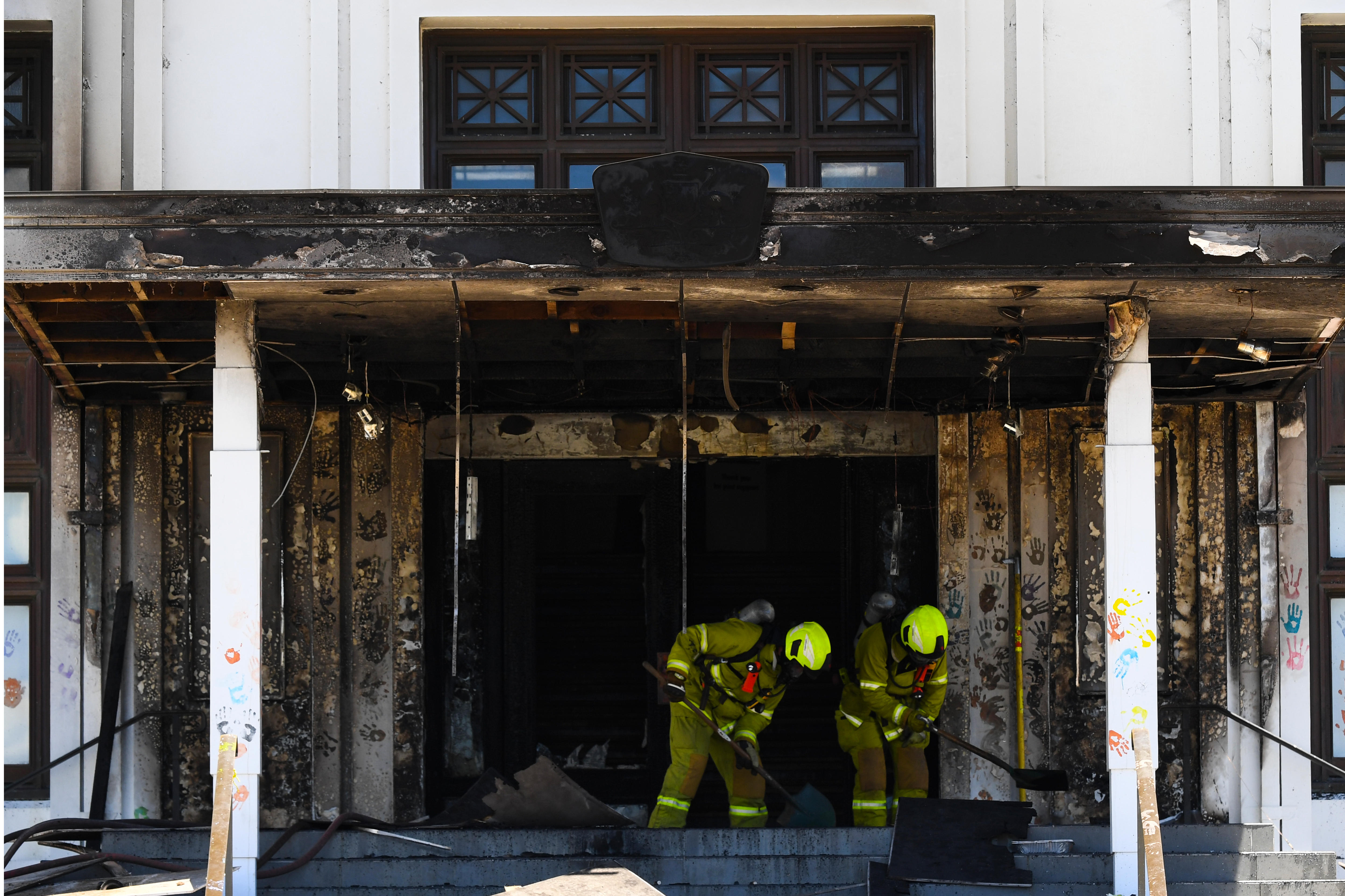 Firefighters clean the damage from a burnt-out doorway.