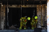 Firefighters clean the damage from a burnt-out doorway.