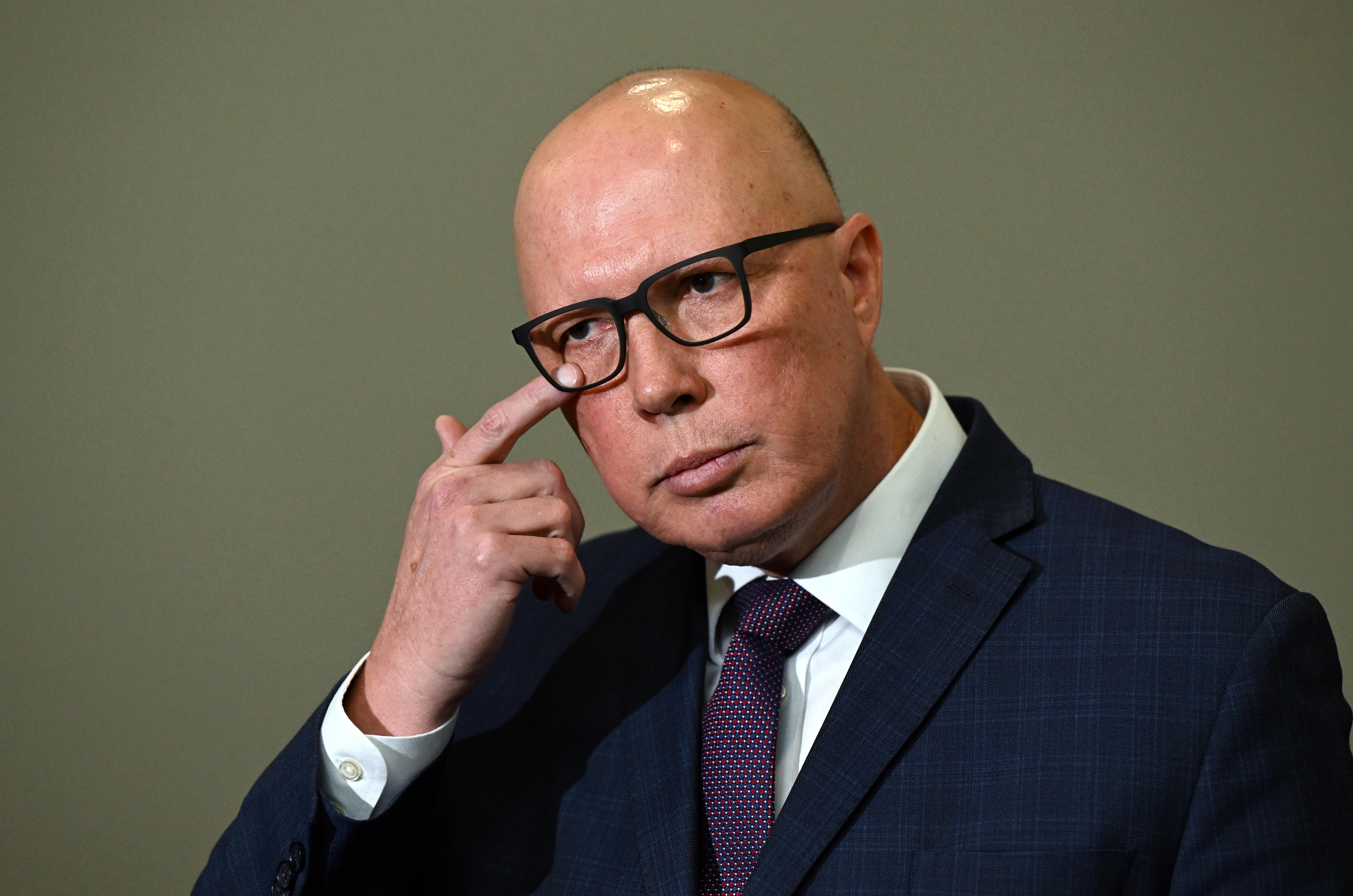 Peter Dutton rubs his eye.
