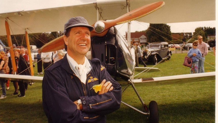 Museum founder John Fisher standing in front of a plane.