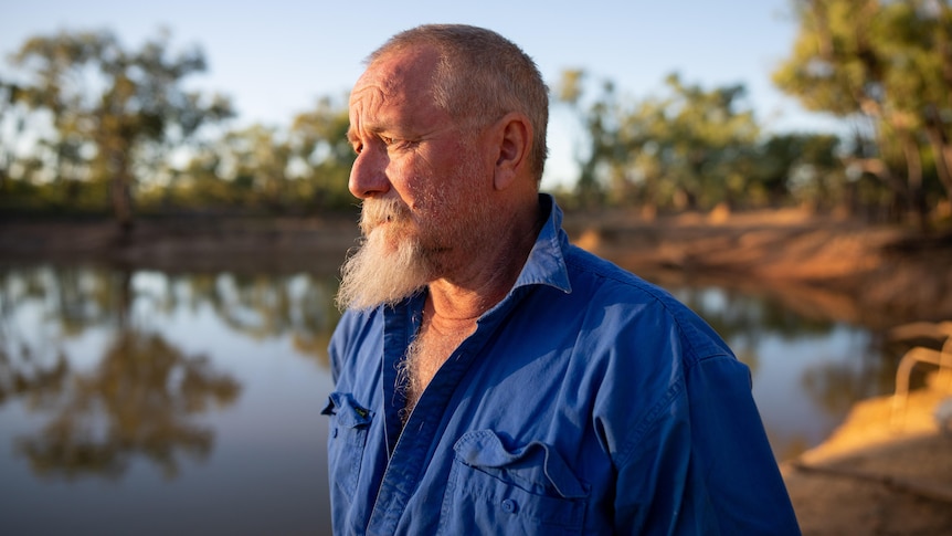 A middle-aged pastoralist looks with concern over a body of water at Gorrie Station. 