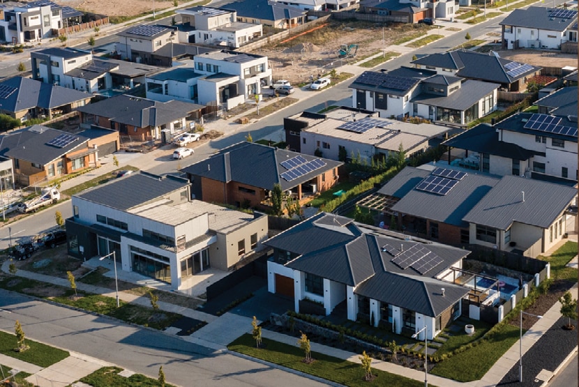 An aerial view of houses with solar panels on their rooftops.