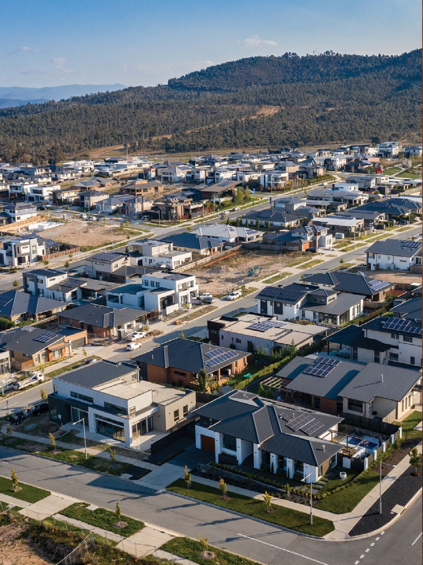 An aerial view of houses with solar panels on their rooftops.