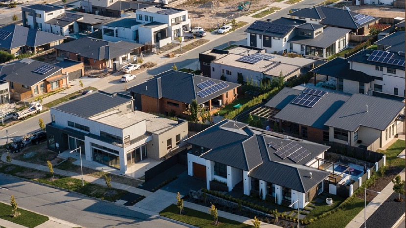 An aerial view of houses with solar panels on their rooftops.