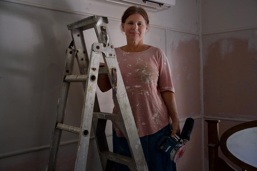 Lee-Ann Handley stands on a ladder while painting. 