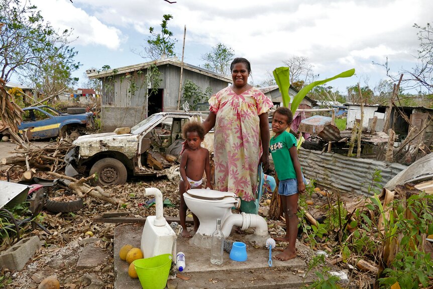 A Port Vila family stand in their destroyed home