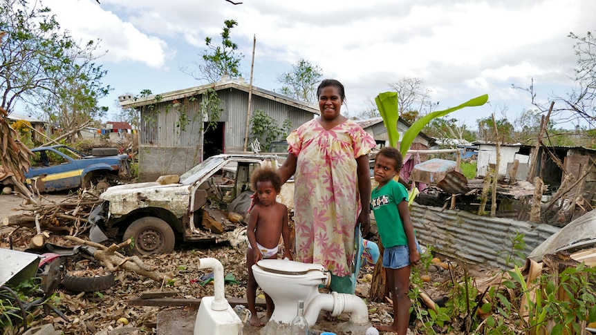 A Port Vila family stand in their destroyed home