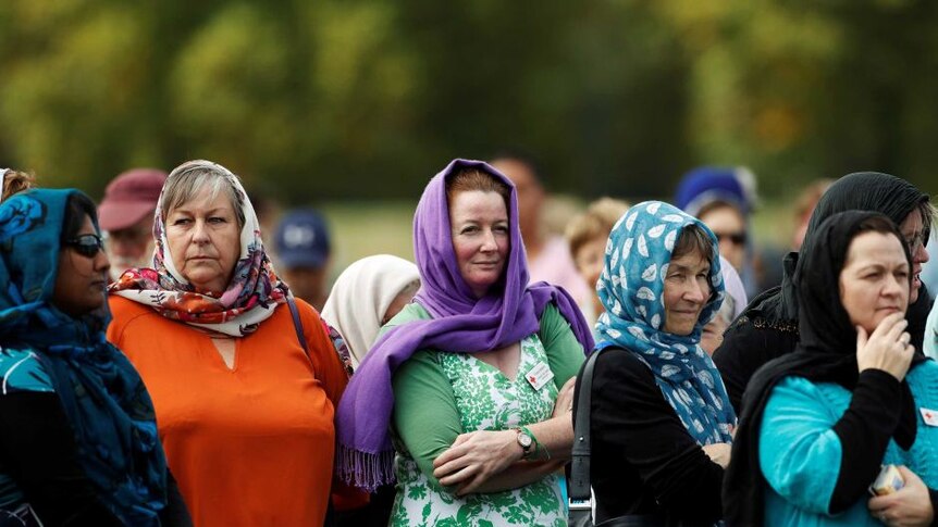 Perempuan yang mengenakan jilbab berdiri di luar masjid Al-Noor di Christchurch.