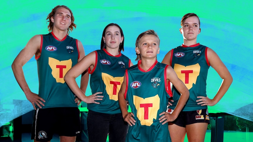 Four children of different ages, wearing the new Tasmania Devils jerseys, pose for a photo.