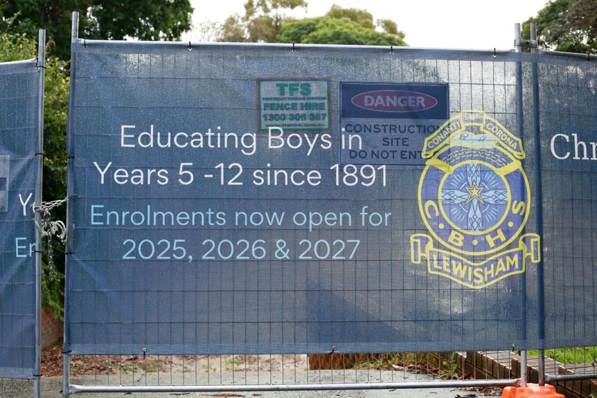 A school banner placed over a construction fence.