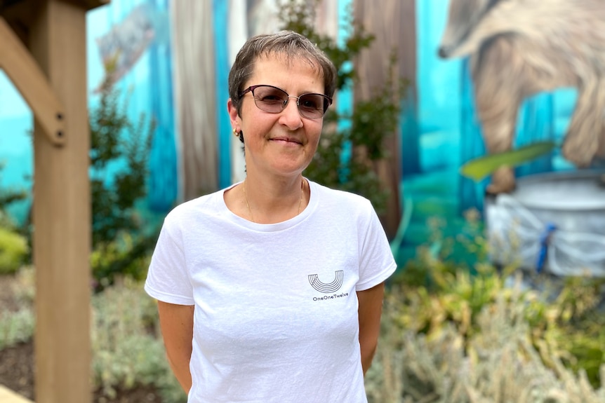 Mina Borromeo stands in front of a mural outside, looking calmly at the camera.