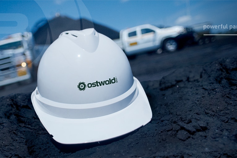 A white hard hat sits in the soil near with a truck and ute in the background with the caption "powerful partnerships"