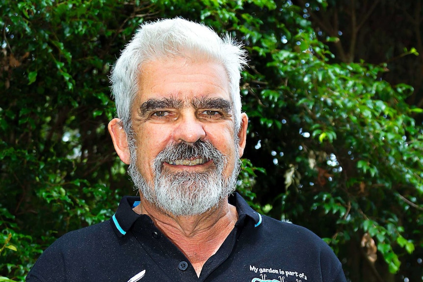 A portrait photo of a man wearing a Pollinator Link navy t-shirt.