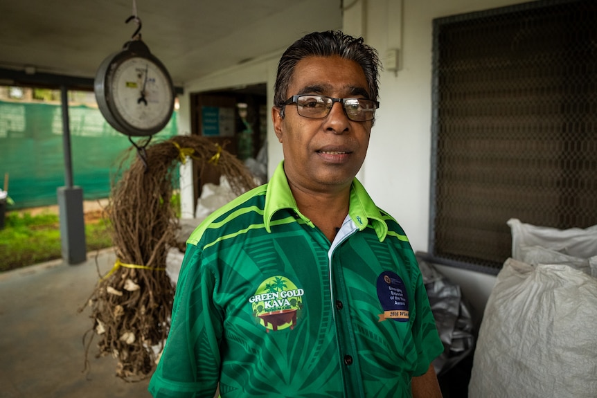 Image of a man wearing a green shirt standing in front of roots.