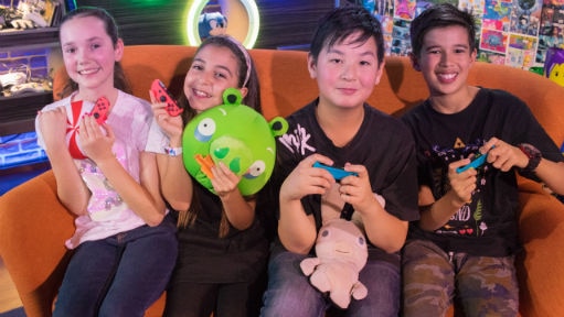 Four kids smiling holding controllers and toys