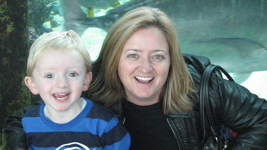 A young boy and a woman smile at the camera.