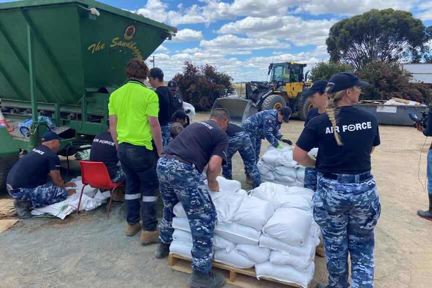 Members of the airforce around a pallet of white sand bags. 