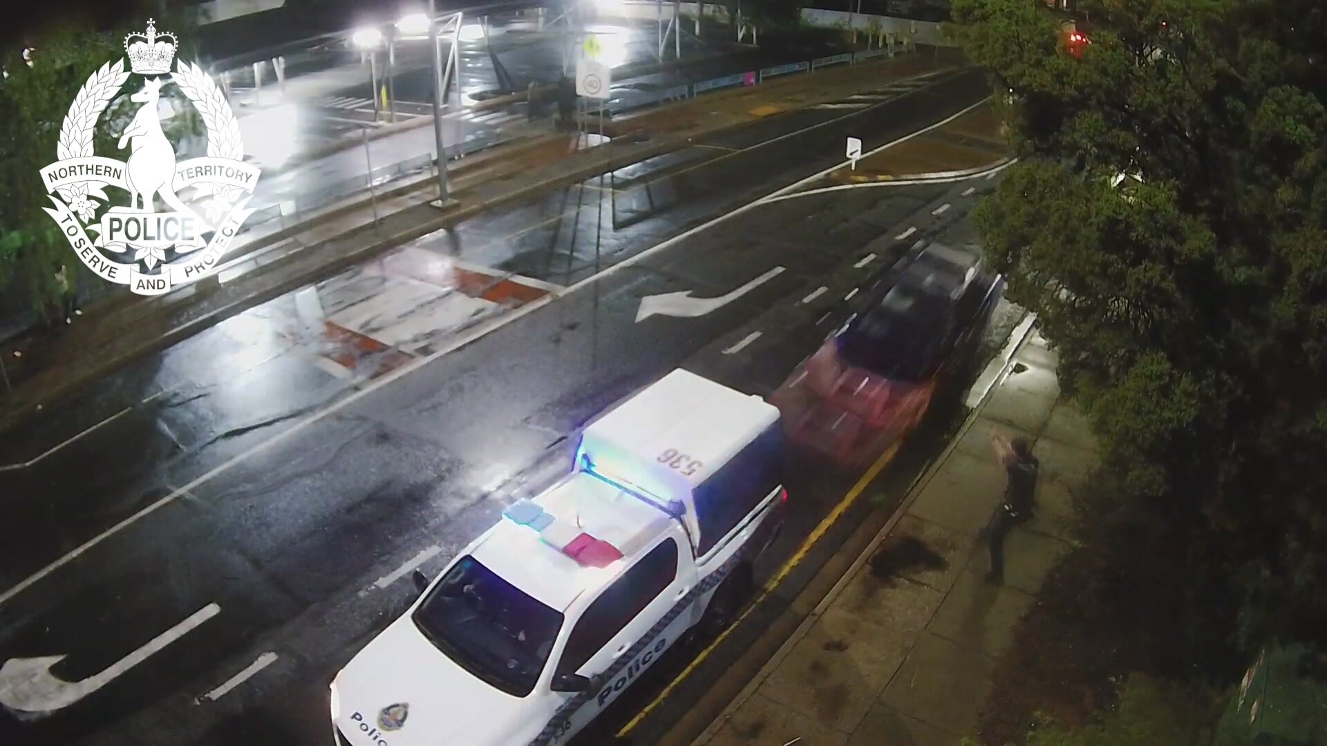 A still from CCTV shows a blue ute speeding towards a stationary police car.