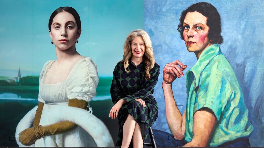 A woman sits between two large painted portraits of two other women.