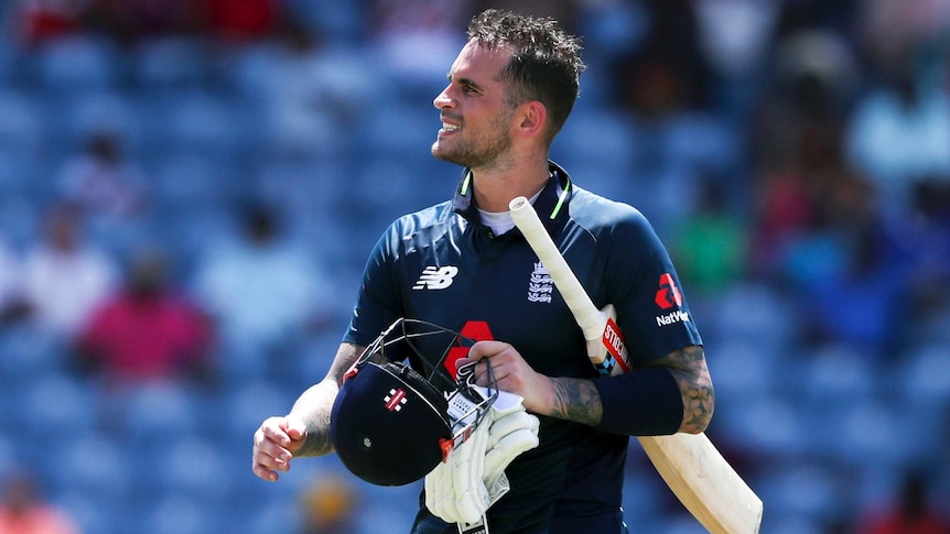 Batsman walks off with his bat, helmet and gloves in his hands after being dismissed.