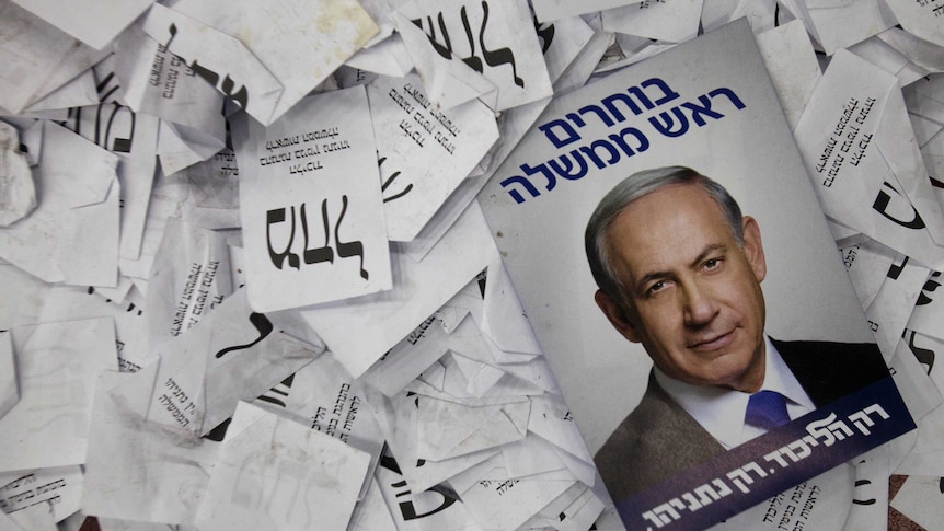 An election campaign poster with the image of Israeli PM Netanyahu lies among ballot papers at his party's election headquarters