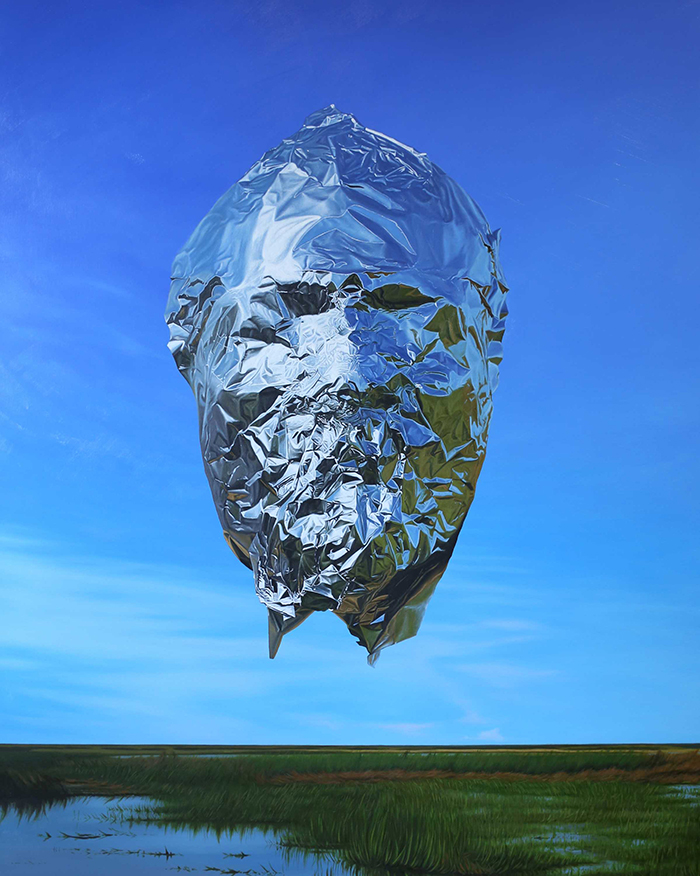A portrait showing a silver foil face floating in a blue sky.