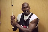 Michael Jordan holds a baseball bat and smokes a cigar in the Chicago Bulls' locker room.
