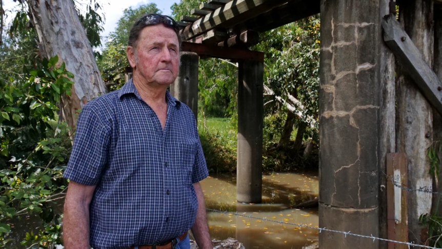 a man stands near a bridge looking off into the distance