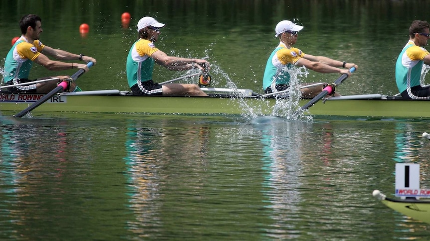 Three men in a green, yellow and white uniforms stroke together on a rowing boat.