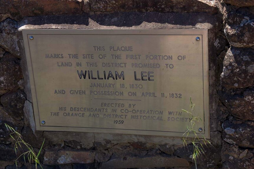 Old metal plaque set into a rock wall with the inscription to William Lee