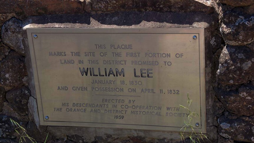 Old metal plaque set into a rock wall with the inscription to William Lee