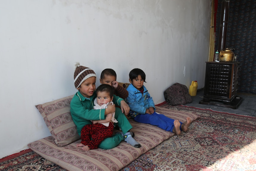 Shaida sits on the floor with her siblings aged 12, six and three years old.