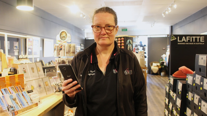 A woman stands in a shop and looks frustrated.