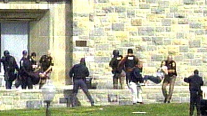 Police carry students out of a building at Virginia Tech, where a gunman killed 32 people