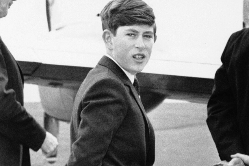 A young Prince Charles walks with his hands crossed behind his back 