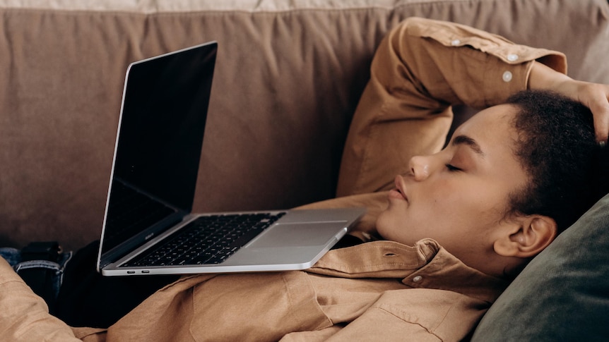 Woman looking exhausted in front of laptop on couch