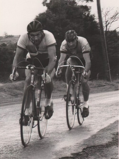 A black and white photo of two cyclists racing.
