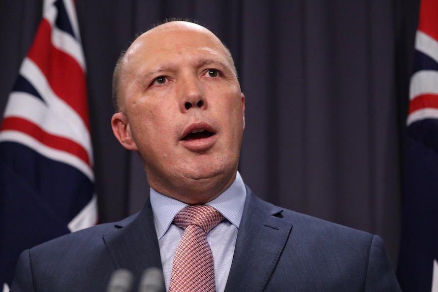 Peter Dutton speaks in front of Australian flags