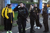 Dortmund players and police stand outside the team bus after it was hit by explosions.