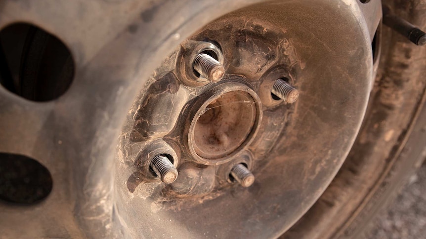 A dusty car wheel with the wheel nuts removed