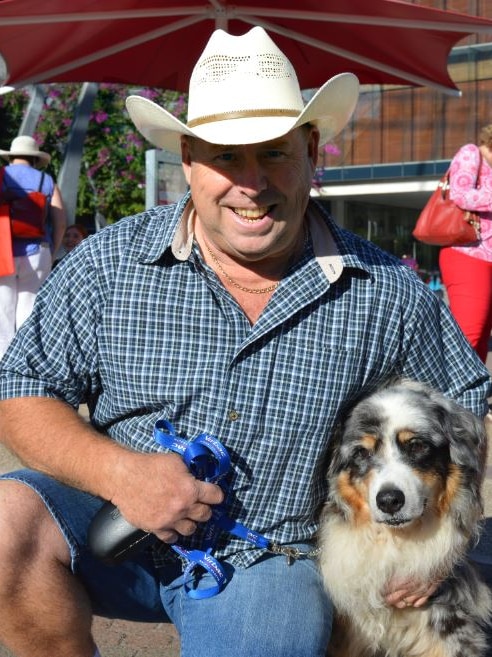 Man in cowboy hat kneels to level of dog