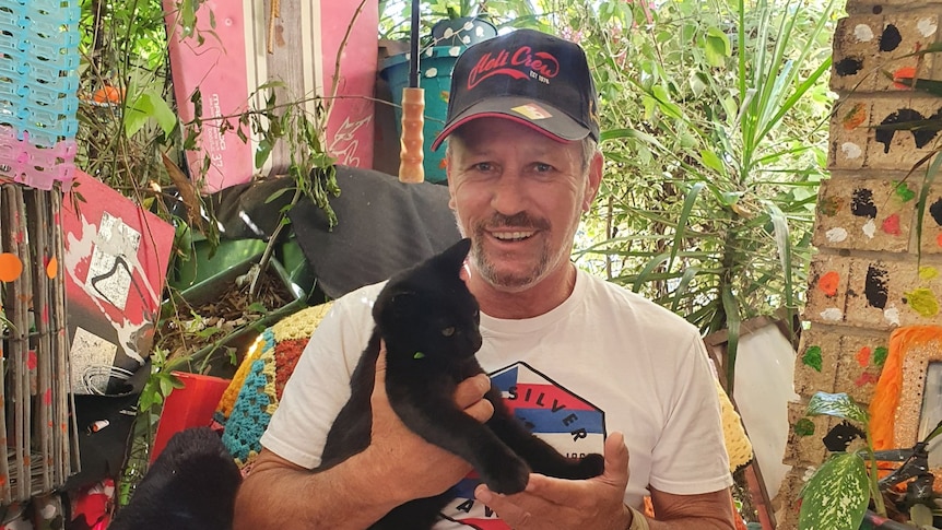 Tweed man Barry Wood relaxes in an armchair in his new unit cuddling Bear the black cat.