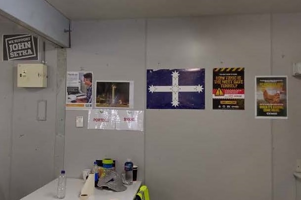 posters depicting slogans and the eureka flag on the wall of a construction site tea room