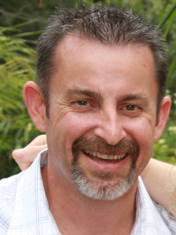 A man of late middle age with a salt-and-pepper goatee and short hair, smiling.