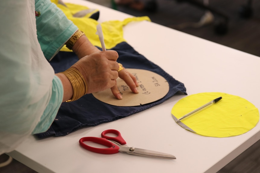 A woman works on a piece on a fabric